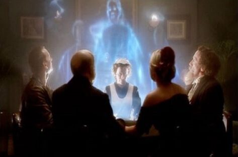 Círculo de cinco personas en sesión de espiritismo con espectros de espíritus alrededor de ellos